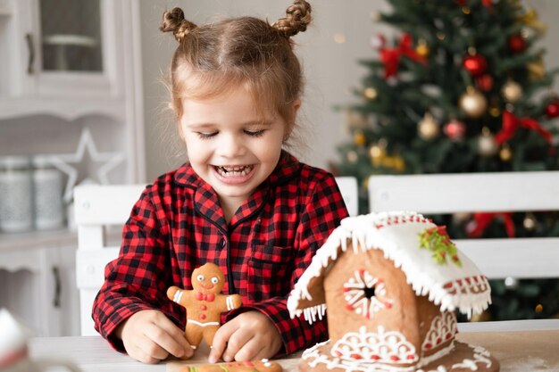 menina de pijama vermelho segurando biscoito de gengibre de natal decorado para homens