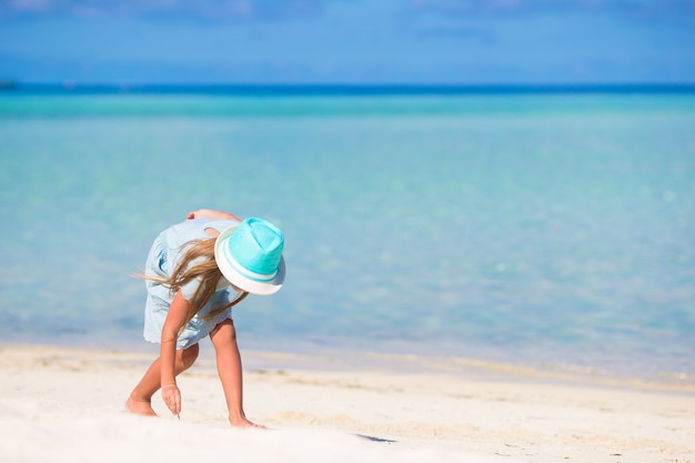 Menina de sorriso feliz adorável no chapéu em férias da praia