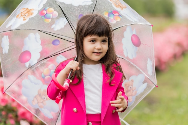 Menina de terno fúcsia brilhante sai sob um banner de cartão de guarda-chuva transparente