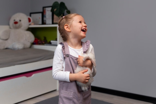 Menina de tiro médio brincando com coelho