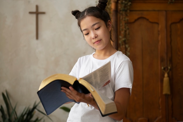 Menina de tiro médio lendo a bíblia cristã