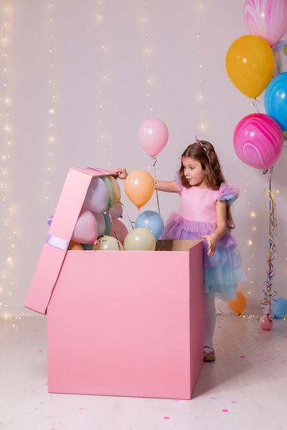 Menina de vestido abre uma enorme caixa rosa com uma criança surpresa recebe um presente de aniversário