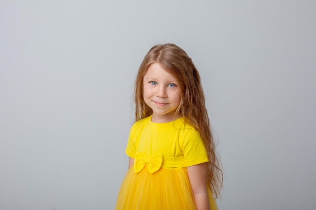 menina de vestido amarelo mostra diferentes emoções fundo branco alegria sonhando surpresa