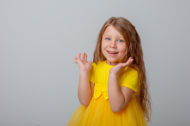 menina de vestido amarelo mostra diferentes emoções fundo branco feliz