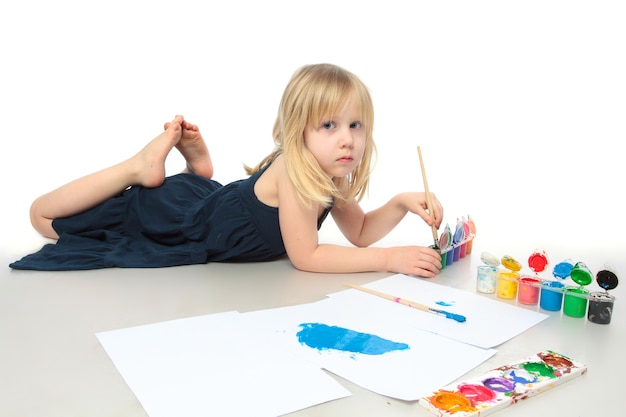 Menina de vestido azul desenhando uma tinta colorida