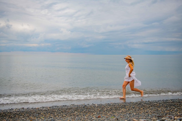 Menina de vestido branco a correr na praia