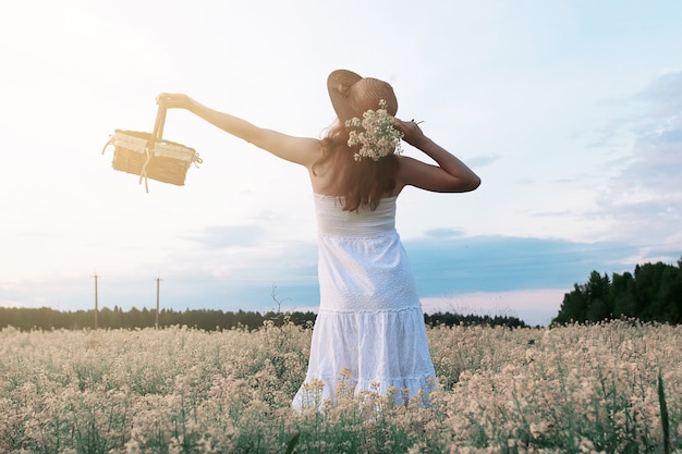 Menina de vestido branco em campo de flores amarelas desabrochando
