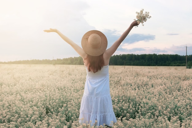 Menina de vestido branco em campo de flores amarelas desabrochando