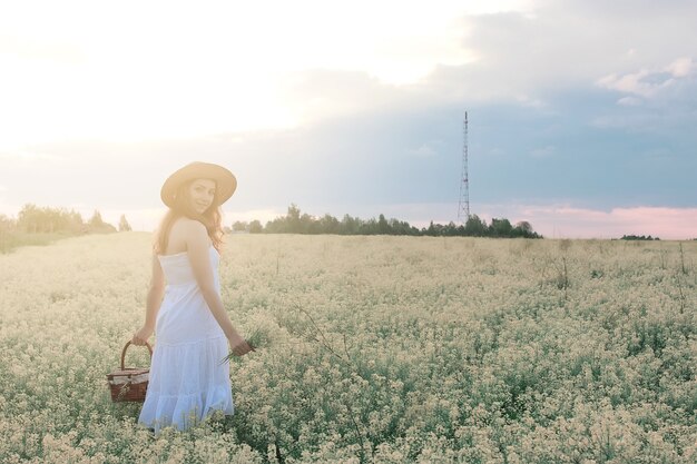 Menina de vestido branco em campo de flores amarelas desabrochando