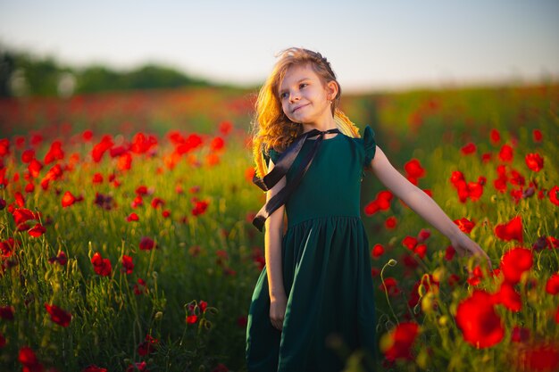 Menina de vestido e chapéu de palha ao ar livre em Poppy Field no pôr do sol