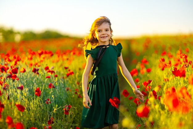 Menina de vestido e chapéu de palha ao ar livre em Poppy Field no pôr do sol