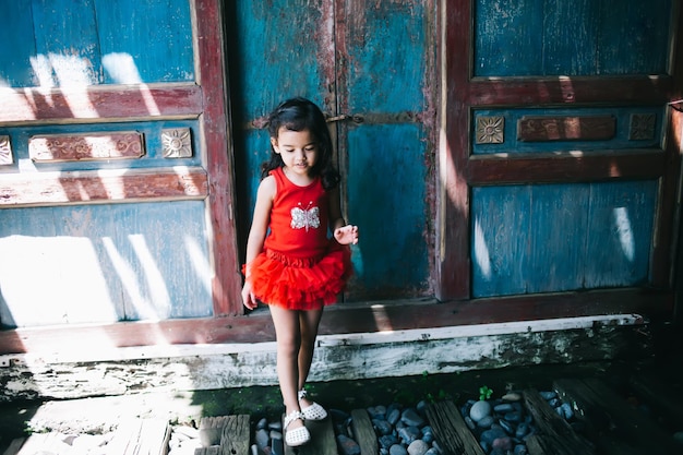 Menina de vestido em pé no fundo da parede enferrujada