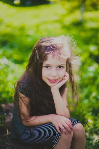 Foto menina de vestido escuro com cabelo comprido sentado no jardim primavera