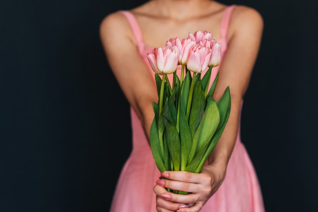Menina de vestido rosa segurando um buquê de tulipas