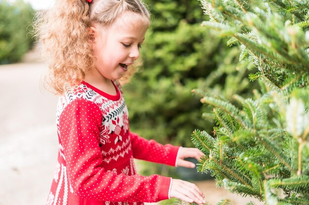 Menina de vestido vermelho na fazenda de árvores de Natal