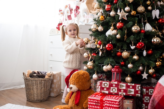 Menina decora a árvore de natal em casa