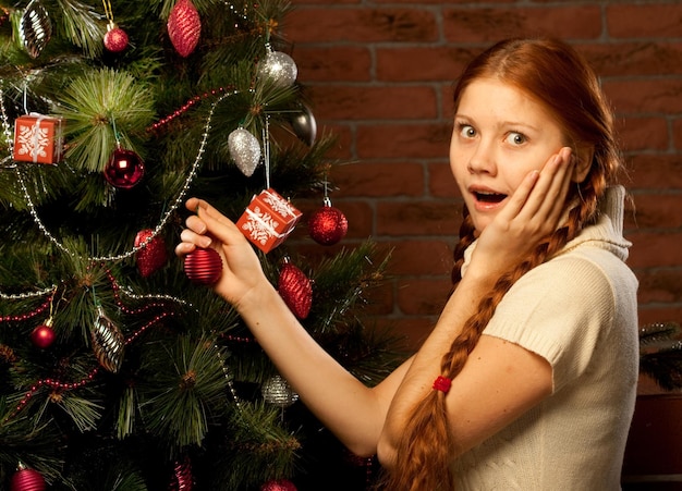 Menina decorar a árvore de Natal no interior de uma casa