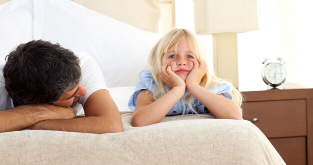 Menina deitada na cama com seu pai