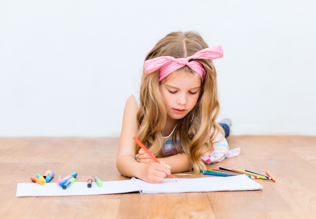 Menina deitada no chão desenhando a lápis