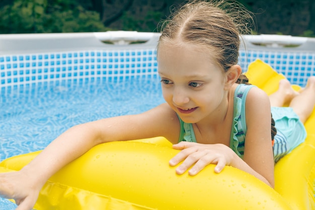 Menina deitada no flutuador da piscina