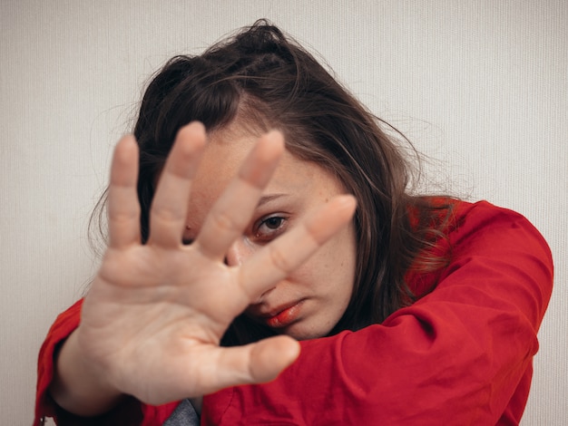 Foto menina deprimida em uma camisa vermelha contra a parede