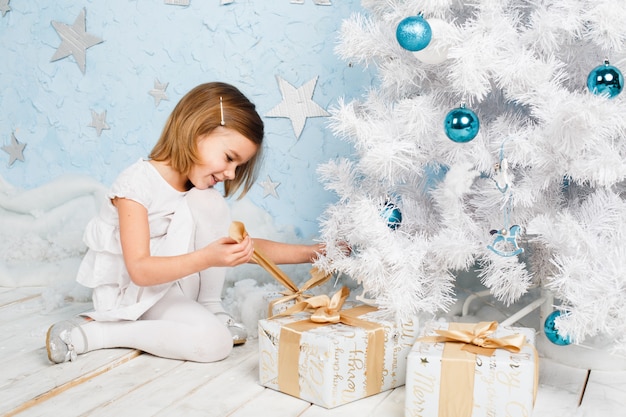 Menina desata a fita em um presente de Natal