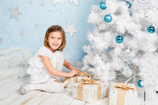 Menina desata a fita em um presente de Natal