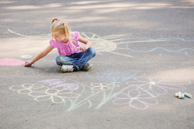 Menina desenha com giz na calçada