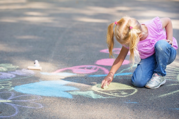 Menina desenha com giz na calçada