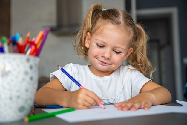 Foto menina desenha com lápis coloridos em casa
