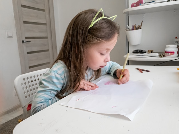 Menina desenha com lápis de cor com a mão esquerda