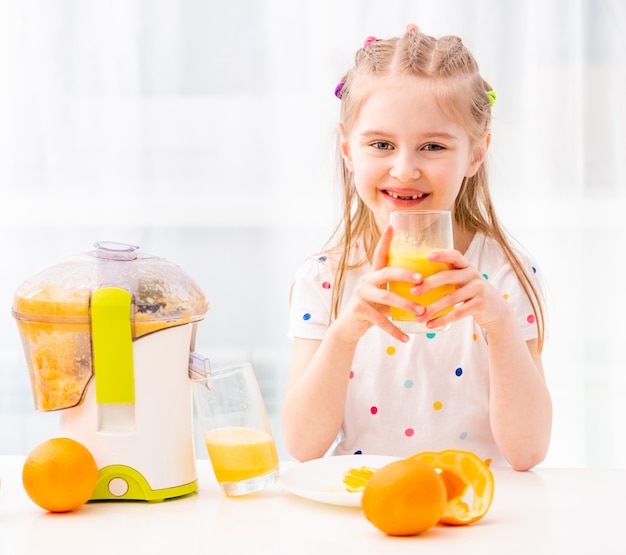 Menina, desfrutando de copo de suco de laranja