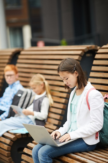 Menina digitando no laptop ao ar livre