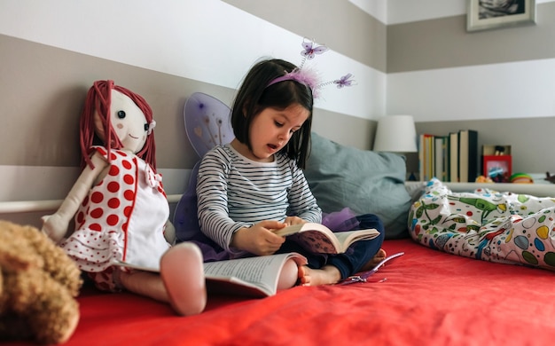 Menina disfarçada lendo um livro para sua boneca