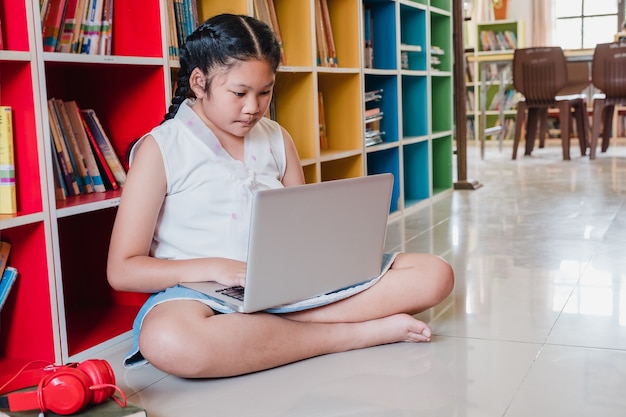 Menina do adolescente do estudante que usa o laptop para a educação na escola.