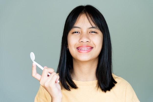 Menina do aparelho dentário sorrindo e olhando para a câmera, ela se sente feliz e tem uma boa atitude com o dentista. Motive as crianças a não ter medo quando precisam ir a uma clínica odontológica.