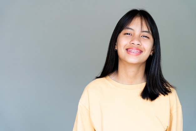 Menina do aparelho dentário sorrindo e olhando para a câmera, ela se sente feliz e tem uma boa atitude com o dentista. Motive as crianças a não ter medo quando precisam ir a uma clínica odontológica.