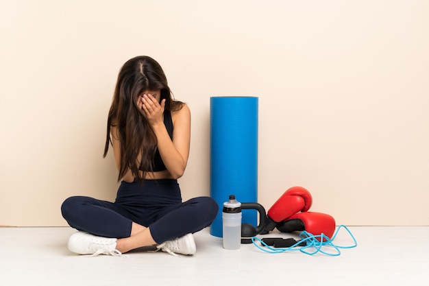 Menina do esporte adolescente sentado no chão com expressão cansada e doente