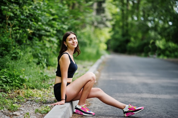 Menina do esporte no sportswear, descansando em um parque verde após o treino na natureza.