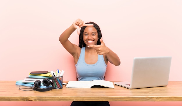 Foto menina do estudante do adolescente do americano africano com cabelo trançado longo em sua face de focalização do local de trabalho