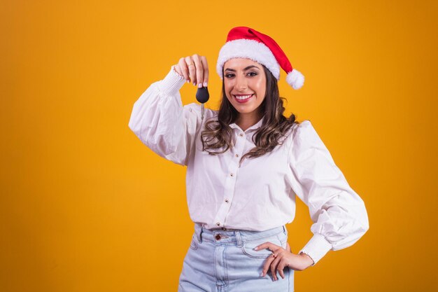 Menina do Natal com chapéu de Papai Noel segurando as chaves do automóvel. Isolado.