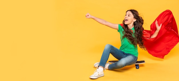 Menina do retrato em traje de herói no skate