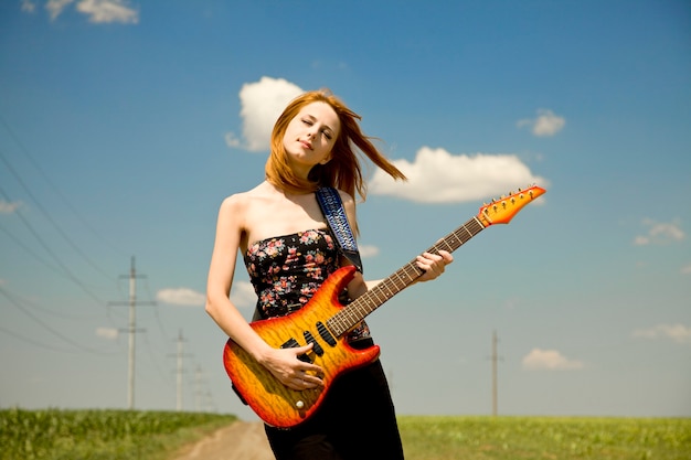 Menina do rock com guitarra na zona rural.