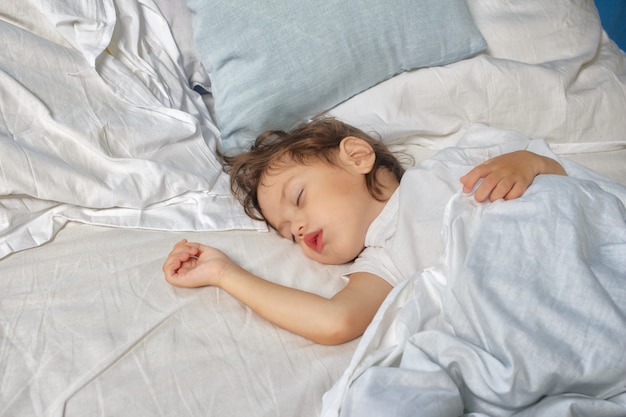 menina dorme na cama. Conceito de sono do bebê.