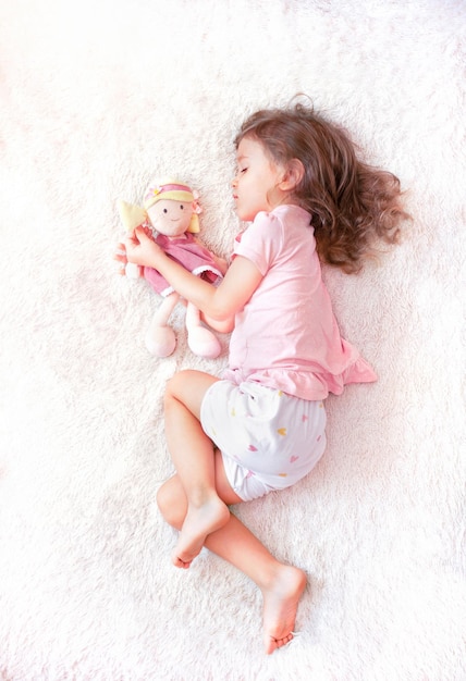 menina dormindo com uma boneca