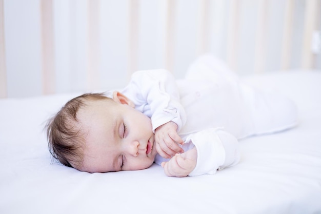 Menina dormindo em uma cama em uma cama de algodão branco doce sono bebê recém-nascido fofo em casa em um berço fechado