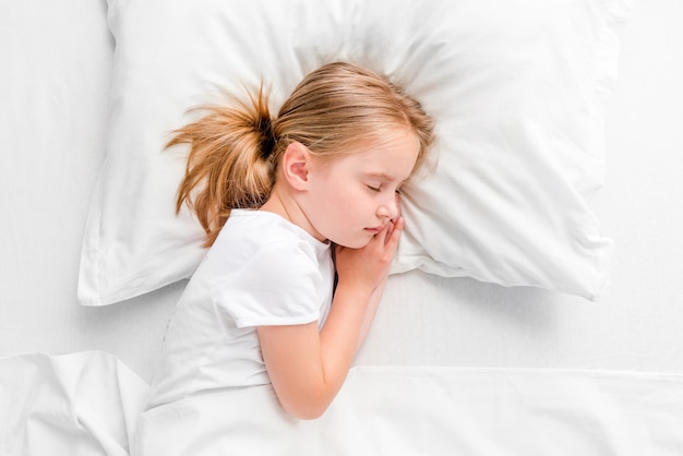 Menina dormindo na cama branca