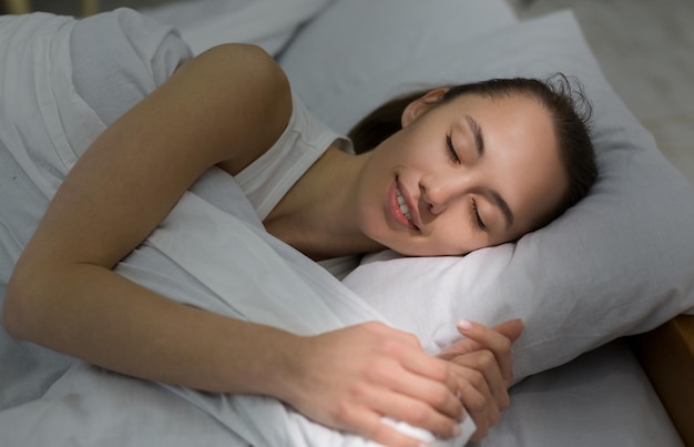 Menina dormindo na cama raio de sol da manhã caindo no rosto