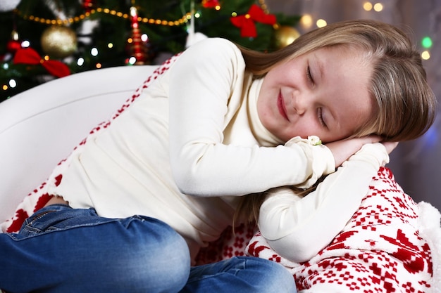 Menina dormindo no fundo da árvore de natal