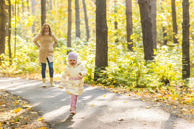 Menina e a mãe brincando no parque outono.